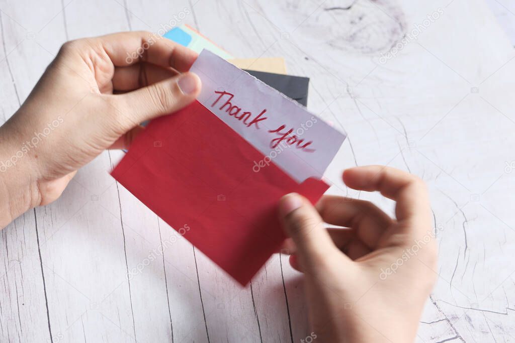 womens hand holding thank you letter , top down 