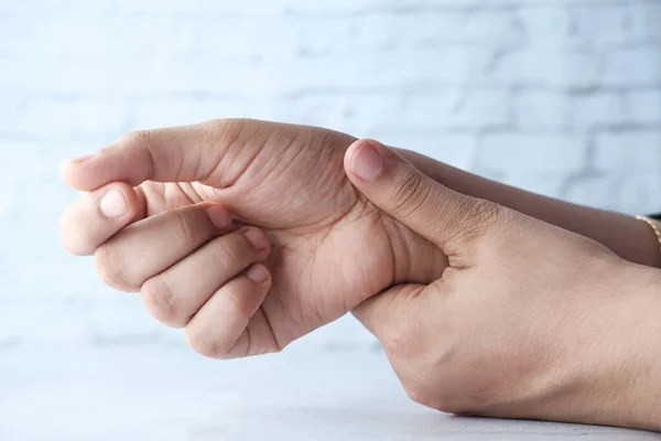 Junge Frauen Hände auf dem Tisch in Schmerzen am Handgelenk, Nahaufnahme — Stockfoto