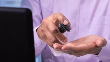 İş adamı ofis masasında dezenfektan jeli kullanıyor. 