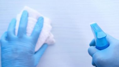 Tek kullanımlık eldivenleri masa yüzeyini temizlemek için dezenfektan spreyi kullanarak verin.,