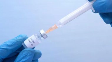 Tıbbi eldivenlerdeki doktor ellerinde şırınga ve aşı tutuyor..