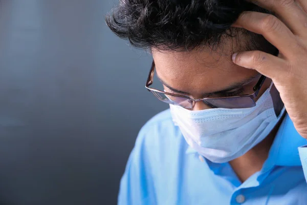 Ένας άρρωστος άνθρωπος με προστατευτική μάσκα στο πρόσωπο κοιτάζει κάτω — Φωτογραφία Αρχείου