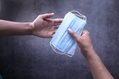 Erkeklerin elleri koruyucu maskeyi aşağı doğru tutar. 
