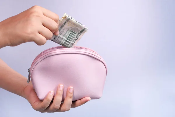 women hand saving cash in wallet isolated in white