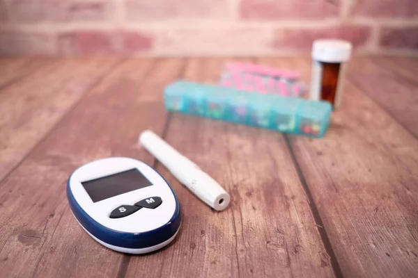 Menutup alat ukur diabetes dan pil pada latar belakang kayu — Stok Foto