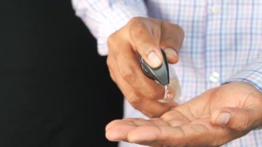 Siyaha izole edilmiş dezenfektan jel kullanarak genç adamın elini kapat. 