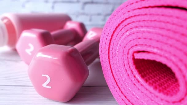 Pink color dumbbell, exercise mat and water bottle on white background — Stock Video