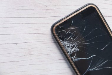 Ahşap arka planda kırılmış akıllı telefonun üst görünümü 