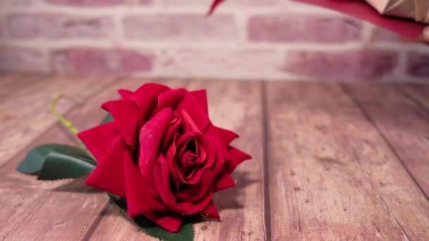 Закрыть розовый цветок и подарочную коробку на столе — стоковое видео