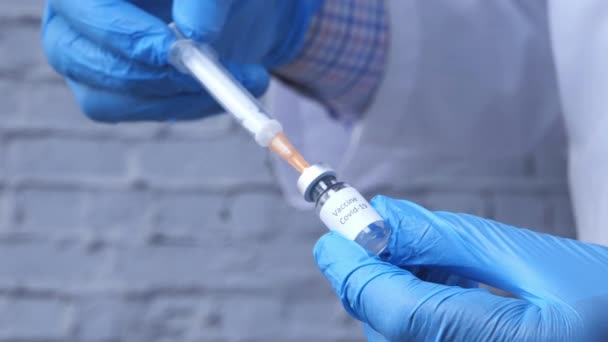 Руки врача в медицинских перчатках держат шприц и вакцину. — стоковое видео