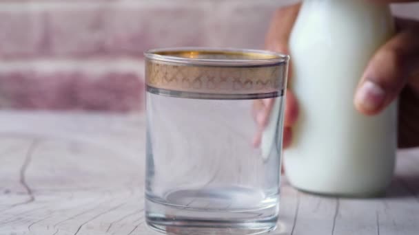 Закрыть низким содержанием жира молоко наливая в стекло на деревянный стол — стоковое видео