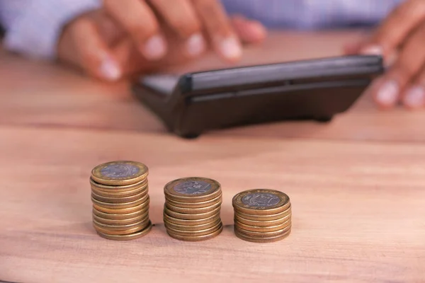 Stack of coins on table and man using calculator on background — Stock Photo, Image