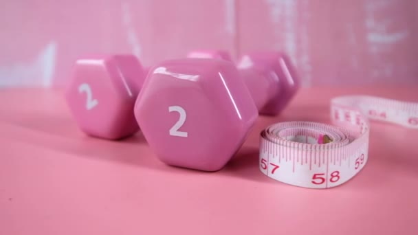 Concepto fitness con mancuerna y cinta métrica en rosa — Vídeos de Stock