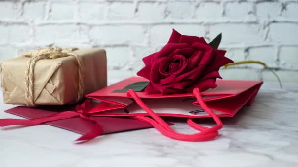 Geschenkdoos, envelop en rozenbloem op witte achtergrond — Stockvideo
