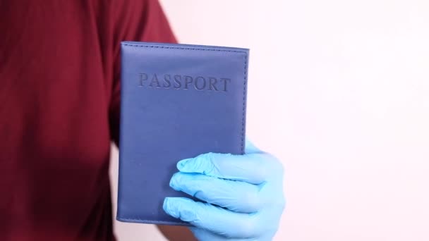 Tangan di sarung tangan bedah biru memegang paspor di tangan. — Stok Video