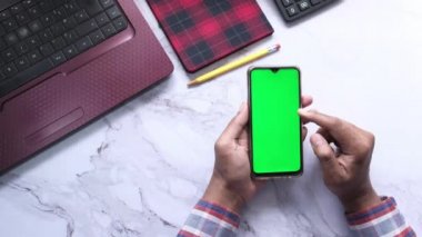 Ofis masasında akıllı telefon kullanan bir adamın üst görüntüsü. 