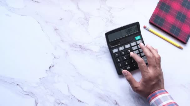 Vista superior de la mano del hombre utilizando la calculadora sobre fondo de baldosa — Vídeos de Stock