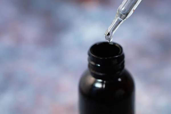 Drop falls from a pipette into a cosmetic bottle — Stock Photo, Image