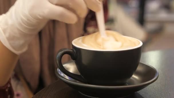 Vrouwen hand in beschermende handschoenen roeren koffie met lepel. — Stockvideo