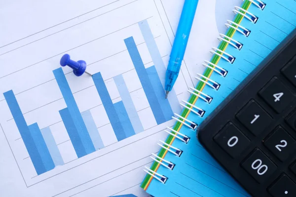 Pénzügyi grafikon, számológép és jegyzettömb az asztalon — Stock Fotó