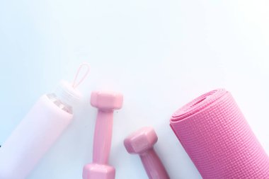 Pembe halterler, spor paspası ve beyaz arka planda su şişesi. 