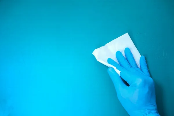 Ruka v modrých gumových rukavicích čistící stůl s látkou — Stock fotografie