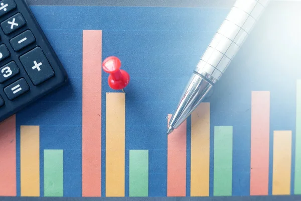 Pénzügyi grafikon, számológép és toll az asztalon — Stock Fotó