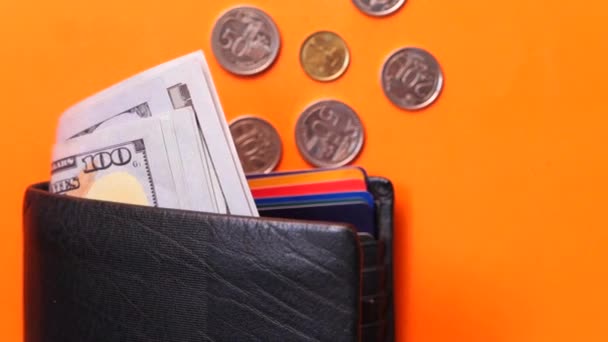 Gotówka w portfelu i monety na pomarańczowym tle — Wideo stockowe
