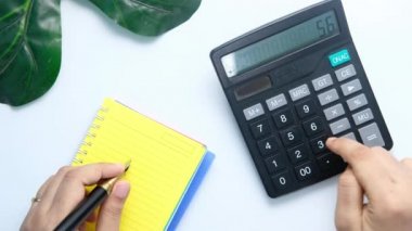 Kadınlar hesap makinesi kullanıp not defterine yazı yazıyorlar. 