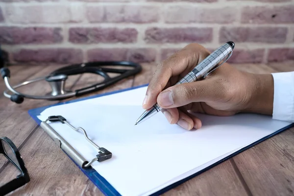 Médico mão prescrição escrita na mesa, close-up. — Fotografia de Stock