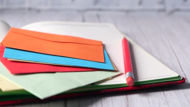 Amplop dan notepad berwarna-warni pada tabel kayu — Stok Video