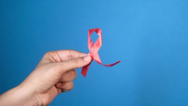 Mão segurando fita HIV vermelho com espaço de cópia no fundo azul — Vídeo de Stock