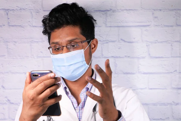 Médico em máscara protetora usando smartphone no hospital. — Fotografia de Stock