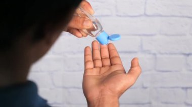 Virüsü önlemek için dezenfektan kullanan genç adamın elini kapat. 