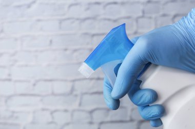 Mavi lastik eldivenler, elinde fotokopi alanı olan sprey şişesi. 