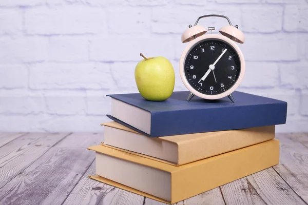 Concept noir à l'école avec pomme et horloge sur pile de livres — Photo