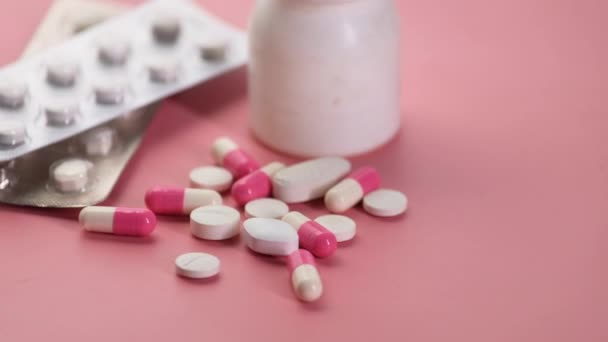 Primer plano de píldoras de colores derramamiento sobre fondo rosa — Vídeo de stock