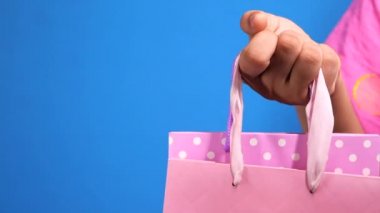 Kadınlar mavi arka planda alışveriş çantasıyla el ele tutuşuyorlar .