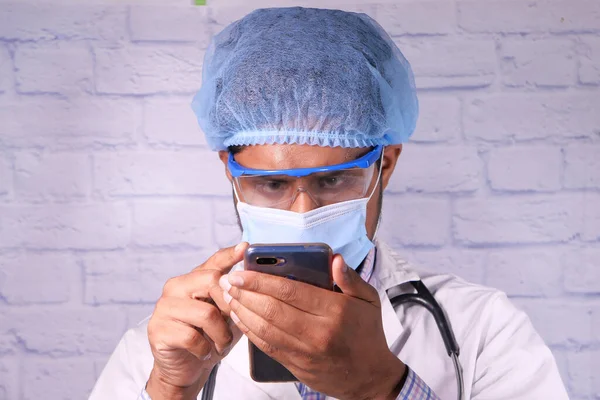 Γιατρός με προστατευτική μάσκα χρησιμοποιώντας smartphone στο νοσοκομείο. — Φωτογραφία Αρχείου