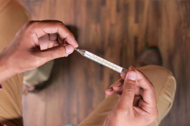 Adamın eli tıbbi termometrede, tepeden tırnağa 