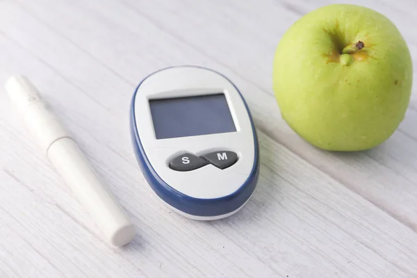 Cukorbetegséget mérő eszközök, alma az asztalon — Stock Fotó