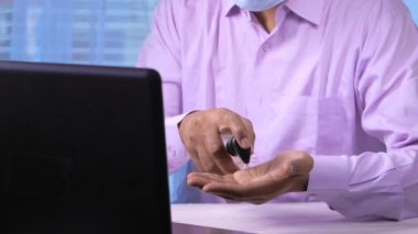  Masada dezenfektan jel kullanan maskeli genç bir adam. 