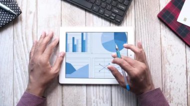 Adam el ile ofis masasında dijital tablet üzerinde çalışıyor, kendi yarattığı grafiği kullanarak. 