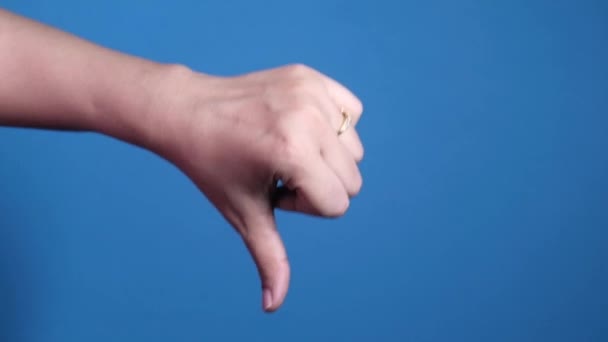 Mână arătând degetul mare în jos semn pe fundal albastru . — Videoclip de stoc