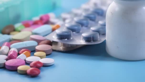 Close-up van kleurrijke pillen morsen op blauwe achtergrond — Stockvideo