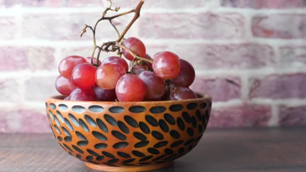 Primer plano de fruta de uva roja en un tazón en la mesa — Vídeo de stock