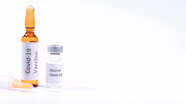 Close up of coronavirus vaccine and syringe on white background — Stock Video