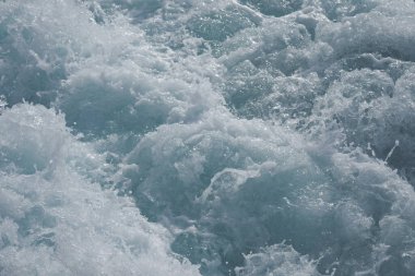 Güçlü dalgalar güneşli bir günde denizde köpüklü bir dalga yaratır..