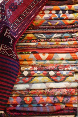 Çeşitli renkli dokuma kumaşlar düzgünce istiflenmiş, karmaşık tasarımlar sergiliyor..