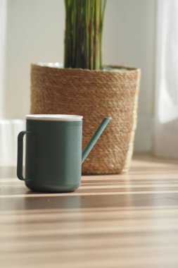 Yeşil bir sulama kabı bir bitkinin yanında oturur..